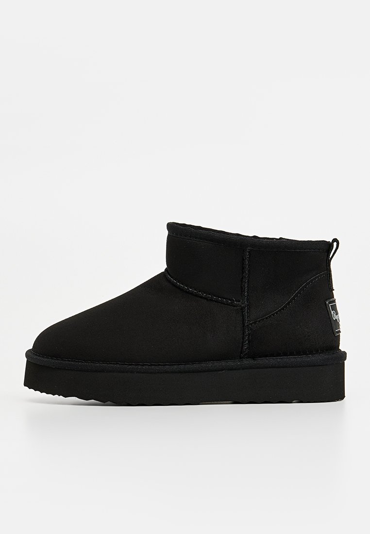 Schwarze Knöchelstiefel mit einer glatten, matten Textur, runder Zehenpartie, kurzem Schaft und einer Lasche zum Anziehen auf der Rückseite; mit einer gestickten Naht. 