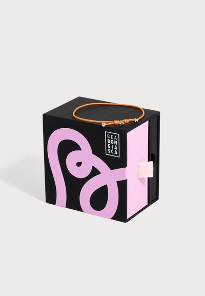 Boîte noire et rose avec un design abstrait et le texte "BEABONGIASC", avec un bracelet cordon orange avec de petites breloques dorées dessus.