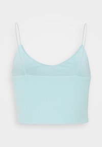Camisole courte côtelée bleu clair avec fines bretelles spaghetti réglables et un détail discret de point zigzag le long de l'encolure.