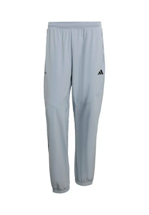 Vaaleanharmaat urheiluhousut, joissa on joustava vyötärönauha, kapenevat lahkeet, sivutaskut ja musta logo vasemmassa reisessä.