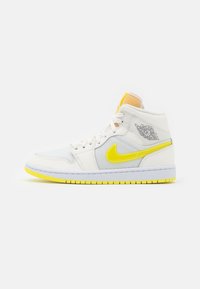 White and yellow high-top sneaker with mesh and leather panels, yellow Nike swoosh, and black Air Jordan wings logo on ankle collar.