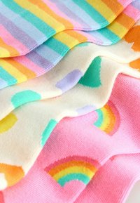 Kolorowe skarpetki poukładane razem. Charakteryzują się pastelowymi paskami, abstrakcyjnymi wzorami i tęczowymi designami. Miękka, teksturowana tkanina.