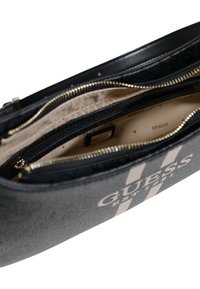 Fekete műbőr clutch arany kiegészítőkkel, cipzáras záródással és bézs belső résszel. A "GUESS" logóval és belső cipzáras zsebbel rendelkezik.