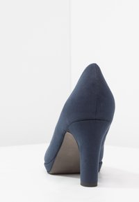 Chaussure à talon haut bleu marine avec une texture en suède, silhouette à bout pointu et hauteur de talon modérée. Finition lisse avec un design sobre.