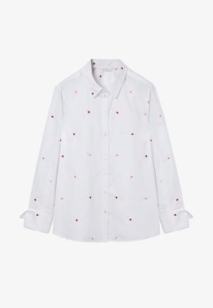 Wit overhemd met lange mouwen, knoopsluiting en kleine rode en roze hartjes verspreid over de stof, met omgeslagen manchetten.