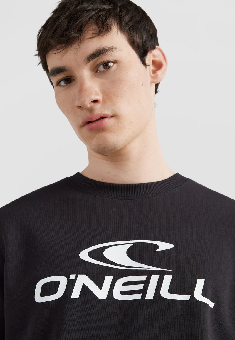 Sudadera negra con cuello redondo, que presenta un destacado estampado en blanco del logo de O'Neill en la parte delantera. Textura suave y ajuste casual.