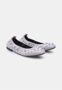 Zapatos planos de lavanda con punta redondeada y un tacón bajo y flexible, adornados con tachuelas metálicas a lo largo del empeine para dar textura y detalle.