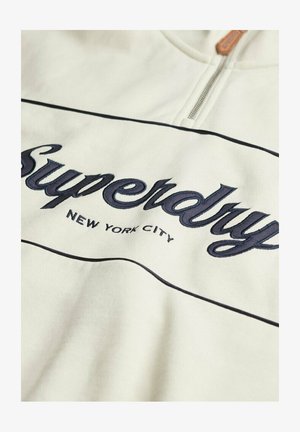 Witte sweatshirt met marineblauwe geborduurde tekst "Superdry" en "NEW YORK CITY". Voorzien van een ritsluiting en zwarte pipingdetails langs de naden.