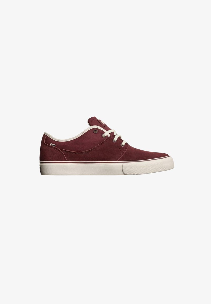 Las zapatillas de ante rojo presentan cordones y suela blancos, además de una punta redondeada. El panel lateral tiene un acabado suave con un detalle de marca minimalista.