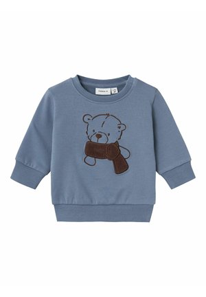 Felpa blu realizzata in morbido cotone, con un orso ricamato marrone che tiene una sciarpa marrone. Dettagli con polsini e bordo a costine.