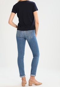 Námořnické tričko s krátkým rukávem spojené s světle modrými skinny džíny, s vykasanými manžetami a béžovými botami na blokovém podpatku. Jednoduchý a přiléhavý design.