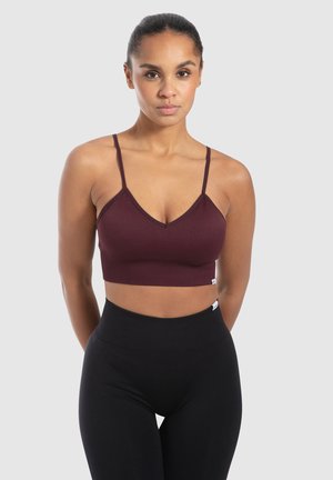 Bordeaux geribbelde bralette met dunne verstelbare schouderbandjes en een V-hals ontwerp. Gecombineerd met hoge zwarte leggings. Soepele textuur.
