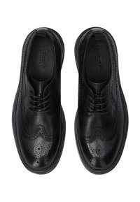 Para czarnych skórzanych butów w stylu wingtip z detalami brogue i sznurowaniem, widzianych z góry na białym tle.