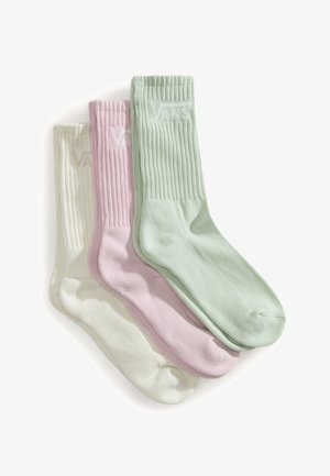 Tre par ribstrikkede crew-sokker i pastelfarver: lys grøn, lys pink og off-white, arrangeret overlappende på en hvid baggrund.