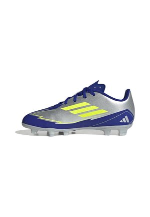 Botas de fútbol plateadas y azules con rayas amarillas, cordones azules y tacos moldeados en la suela, vistas desde el lado interior.