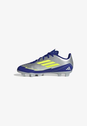 Zilverkleurige en blauwe voetbalschoen met gele strepen, blauwe veters en gevormde noppen onder de zool, gezien vanaf de binnenkant.