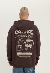 Brown hoodie with a graphic print featuring cartoon coffee cups and text. Made of soft fabric, it has a front kangaroo pocket and drawstring hood.