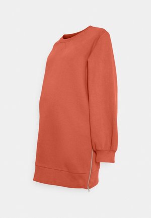 Zwangerschaps-sweater met lange mouwen in roestkleur, met geribbelde boorden en zoom, met een zijritsdétail op een witte achtergrond.