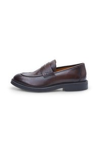 Mocassin en cuir marron avec une texture lisse, un bout arrondi et des détails à double sangle ; doté d'une semelle en caoutchouc noir et d'accents cousus.