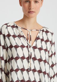 Patroon blouse in crème, met geometrische vormen in bordeauxrood en grijs. Losse pasvorm met een striknek en wijde mouwen. Soepele textuur.