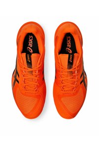 Baskets de sport orange avec une tige en mesh respirant, des accents noirs, des lacets plats et une semelle texturée, conçues pour la performance et le confort.