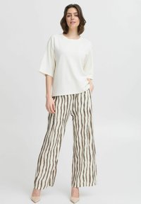 White, loose-fitting short-sleeve top paired with wide-leg pants featuring a vertical brown and cream stripe pattern. Heels complete the outfit.