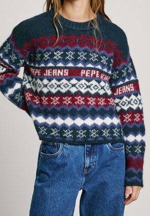 Pull en maille avec des motifs géométriques rouges, blancs, bleus et violets et texte "PEPE JEANS" porté avec un jean en denim bleu.