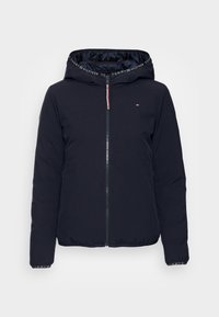 Mørkeblå polstret jakke med lynlås foran, justerbar hætte, elastiske manchetter og logodetaljer på indersiden af hætten. Glat tekstur.