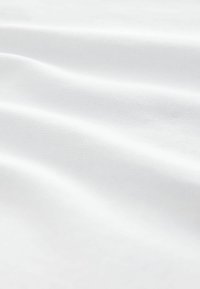 Tela de algodón blanca con una textura suave, mostrando pliegues suaves y un sutil brillo, destacando su ligereza y calidad etérea.