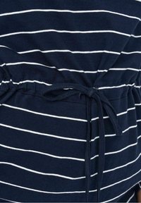 Marineblau gestreifter Stoff mit weißen Linien, ausgestattet mit einem gerafften Bund und einer verstellbaren Bindeschließe für eine figurbetonte Passform. Weiche Baumwollqualität.