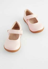 Svetlo roza usnjeni Mary Jane čevlji z ravnim rjavim gumijastim podplatom in nastavljivim trakom čez nart. Gladka površina, zaobljen dizajn prstov.