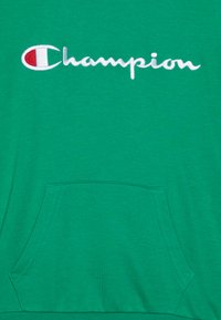 Zelena majica s kapuljačom i izvezenim logom "Champion" u bijeloj boji. Ima prednji kengurufix džep i rebraste manšete. Mekani pamučni materijal.