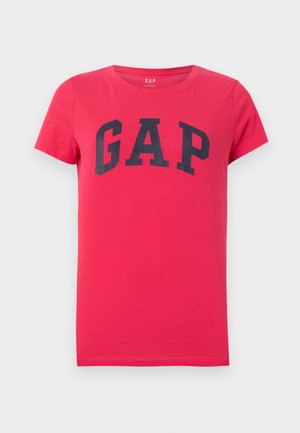 T-shirt rouge à manches courtes avec col rond et grand logo texte noir "GAP" centré sur la poitrine, sur un fond gris clair.