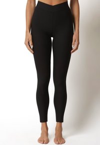 Czarne legginsy o wysokim stanie, wykonane z elastycznego materiału, charakteryzujące się gładką teksturą i dopasowanym krojem, zwężającym się na kostce.