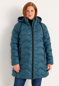 Teal pufferjakke med lynlås foran, hætte og sorte accenter. Den har et quiltet mønster og lommer, designet til varme og komfort.