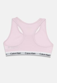 Sutien sport roz cu un design tip racerback, realizat dintr-un material moale. Dispune de un bandă elastică cu marcă alb-negru la baza acestuia.