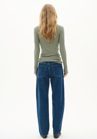 Långärmad ribbad topp i olivgrön, kombinerad med vida blå denimjeans som har bakfickor och en avslappnad passform.