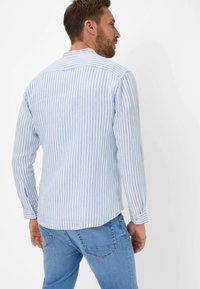 Camicia a maniche lunghe di colore azzurro chiaro con sottili righe bianche, con colletto e polsi abbottonati, realizzata in un tessuto leggero.