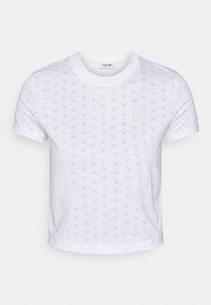 Wit cropped T-shirt met korte mouwen, gemaakt van zacht materiaal, met een gestructureerd patroon van kleine, subtiele V-vormige motieven en een klein logo op de borst.