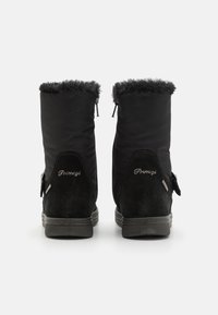 Bottes noires avec un col en fourrure, une combinaison de tissu lisse et de daim, avec une fermeture éclair et un marquage en relief sur le talon.