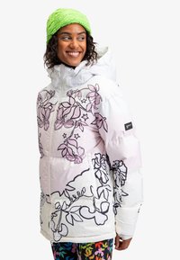 Hvid isoleret jakke med lyserøde blomsterdesigns, lynlås-lommer, hætte og elastiske manchetter. Kombinationen med farverige leggings med mønster og en grøn strikhue.