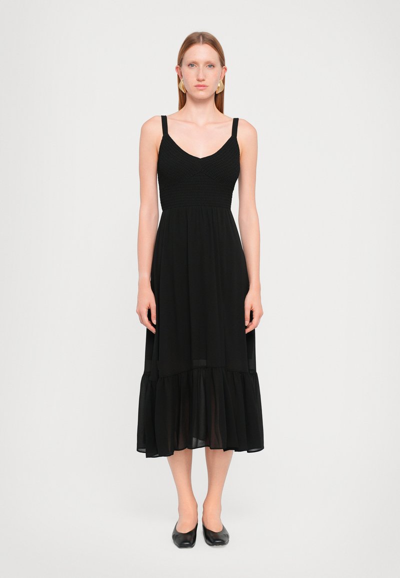 Rochie neagră cu un corp ajustat cu elastic, bretele subțiri și o fustă fluidă cu volane. Fabricată dintr-un material ușor, cu o textură moale.
