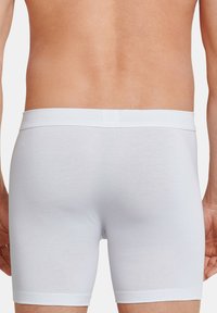 Boxer shorts bianchi in cotone con un design senza cuciture e una cintura elastica, forma aderente e superficie liscia.