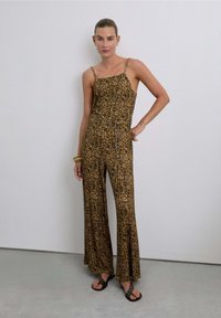 Mono con estampado floral, tirantes finos, cintura ajustada y piernas anchas en tonos marrones y mostaza. Tela suave y ligera.