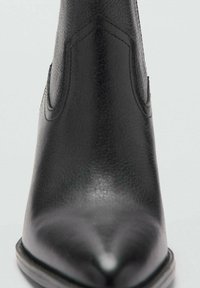 Schwarze Leder-Chelsea-Stiefel mit spitzer Zehenpartie, strukturiertem Finish, elastischen Seiteneinsätzen und flacher Sohle. Minimalistisches Design und glatte Oberfläche.