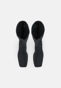 Svarta knähöga stövlar med en slank design, tillverkade av mjukt läder, med en fyrkantig tå och en åtsittande topp med sömdetalj.