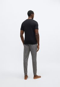 Fekete rövid ujjú póló szürke, geometriai mintás, bordázott szegélyű joggernadrággal párosítva.