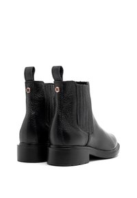 Bottes cheville en cuir noir avec panneaux latéraux élastiques, finition texturée, bout arrondi et petites languettes à l'arrière, avec un détail de logo subtil.