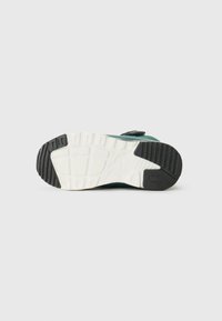 Sneakersohle mit einer strukturierten schwarzen Gummi-Ferse und einer weißen Zwischensohle. Verfügt über ein glattes, türkisfarbenes Obermaterial und auffällige Profilmuster.