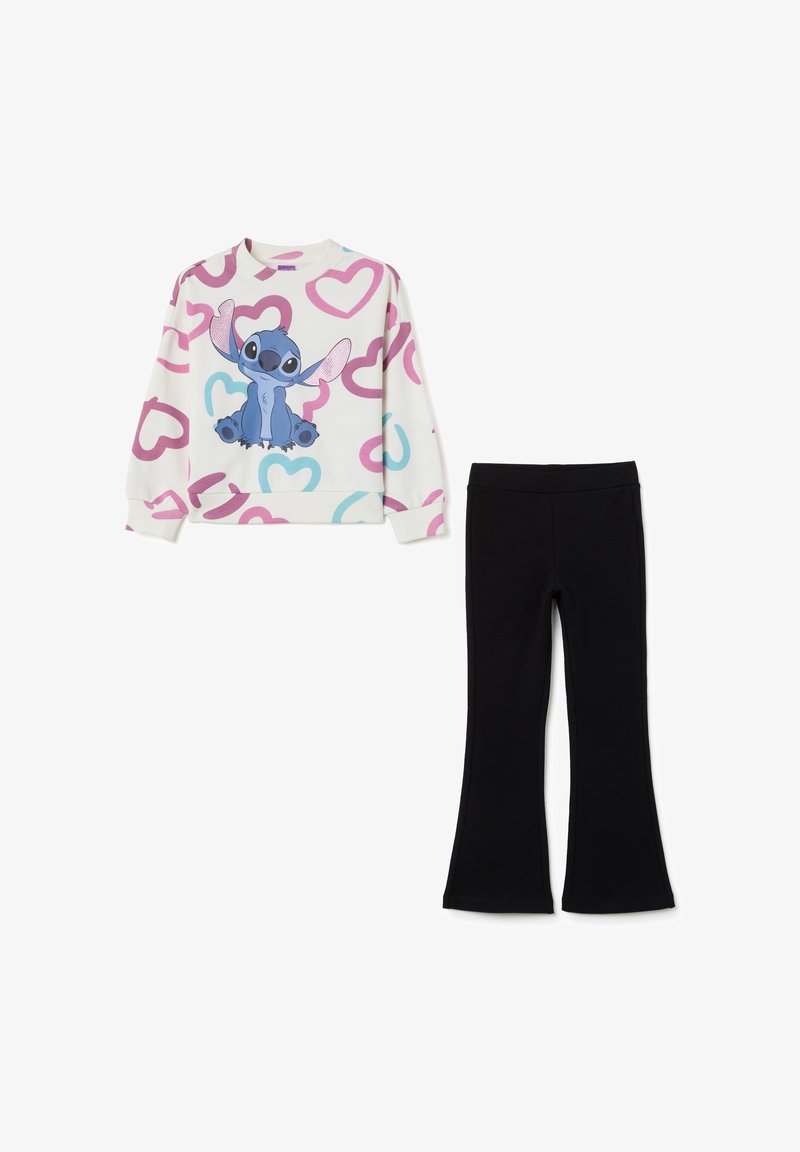 Sudadera en crema con patrones de corazones rosas y azules y un personaje de dibujos animados; combinada con pantalones de campana negros.